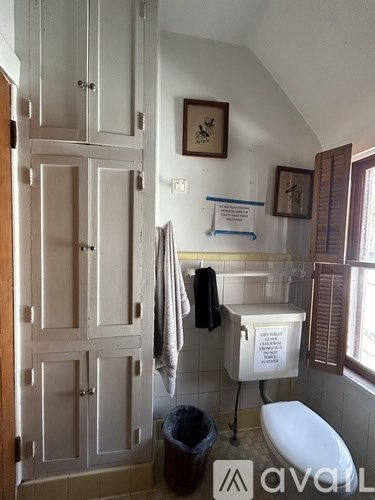 A bathroom with a toilet, sink, and a cabinet.