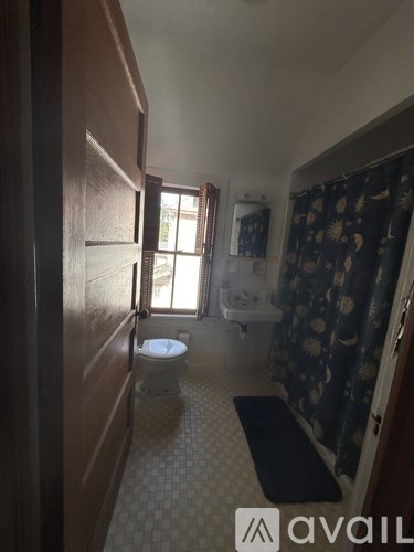 A bathroom with a toilet, sink, and shower curtain.