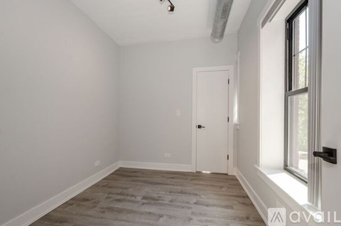 A room with a white door and a window with a black handle.
