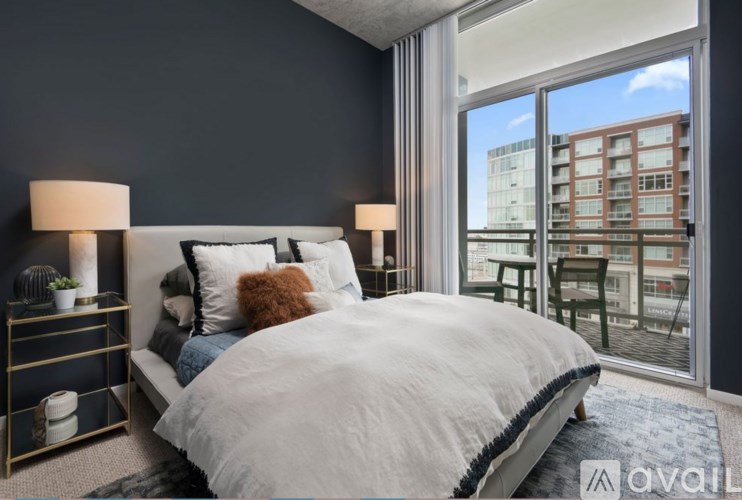 A bedroom with a large bed and a view of a cityscape through the window.