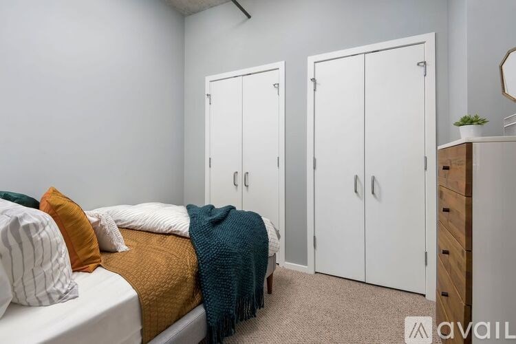A bedroom with a bed, pillows, a blanket, and two white wardrobes.