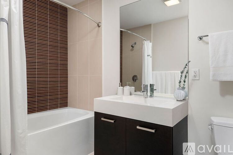 A bathroom with a white tub, sink, and a mirror.