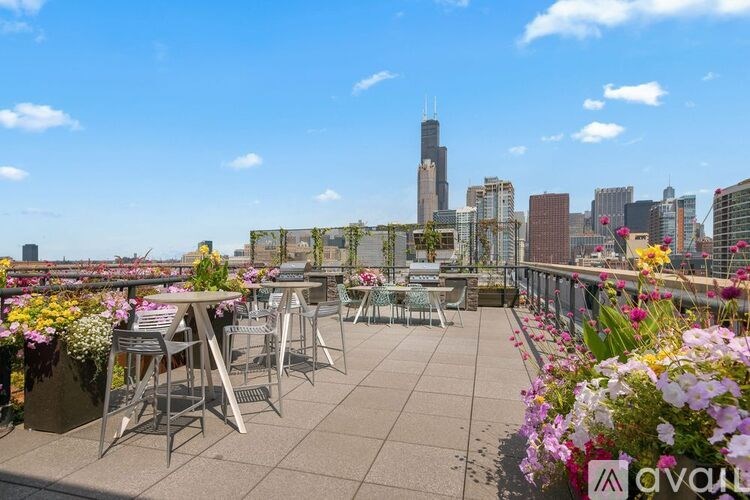 A rooftop patio with tables and chairs overlooking a city skyline.