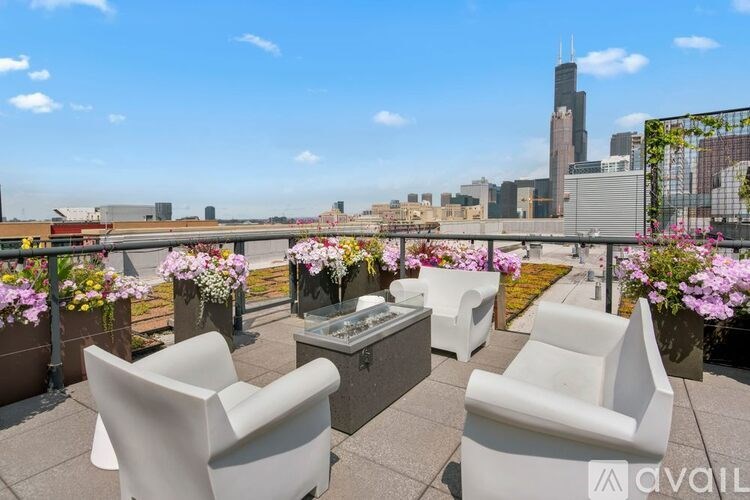 A patio with white chairs and tables overlooking a city skyline.