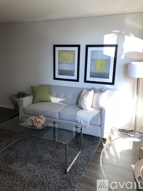 A living room with a grey couch, a glass coffee table, and two framed pictures on the wall.
