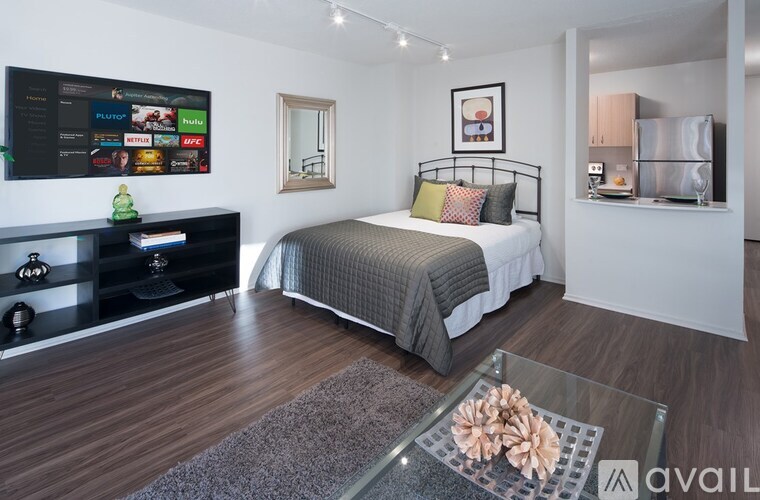 A modern bedroom with a large bed and a flat screen TV mounted on the wall.