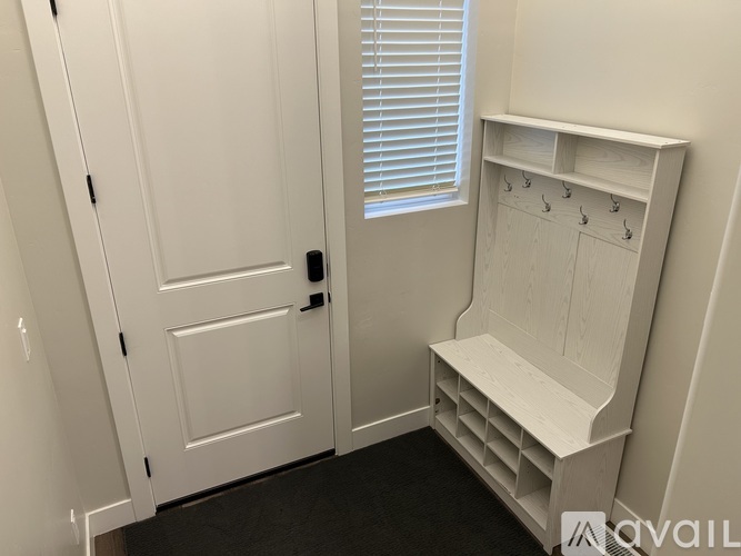 A white door with a black handle is next to a white shelf with hooks.