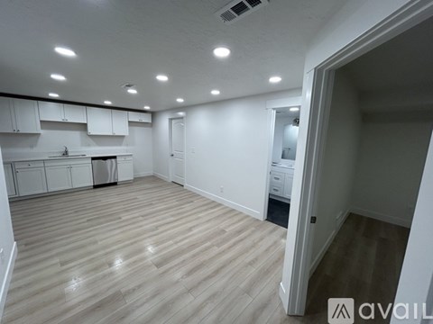 A spacious room with wooden flooring and white walls.