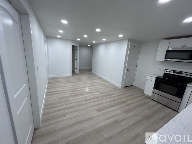 A spacious kitchen with wooden flooring and white cabinetry.