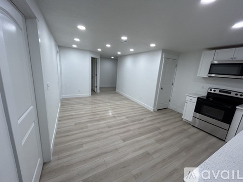 A spacious kitchen with wooden flooring and white cabinetry.