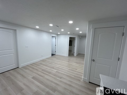 A spacious room with wooden flooring and white walls.