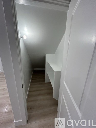 A white hallway with a bench and a door.