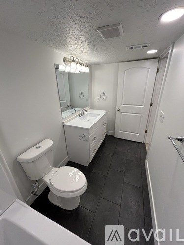 A bathroom with a toilet, sink, mirror, and a white bathtub.