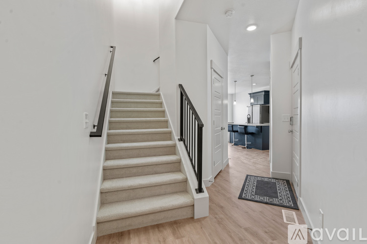 A staircase with a beige carpeted runner and black handrails.