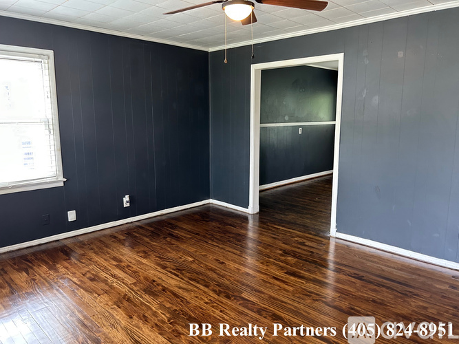 A room with a ceiling fan and a door leading to another room.