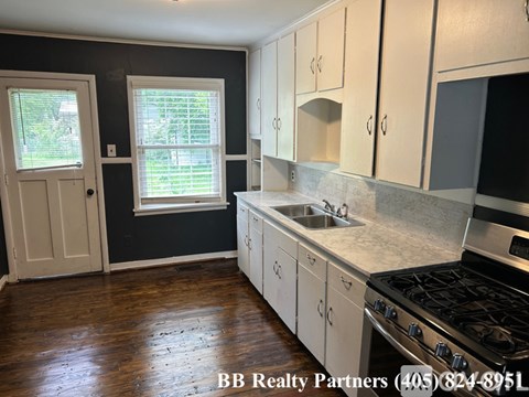 A kitchen with white cabinets and a stove top oven.