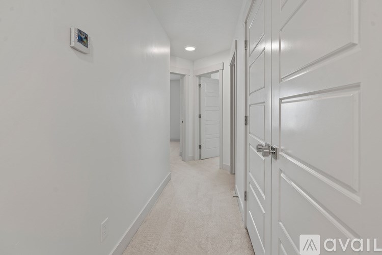 A hallway with white doors and a white wall.