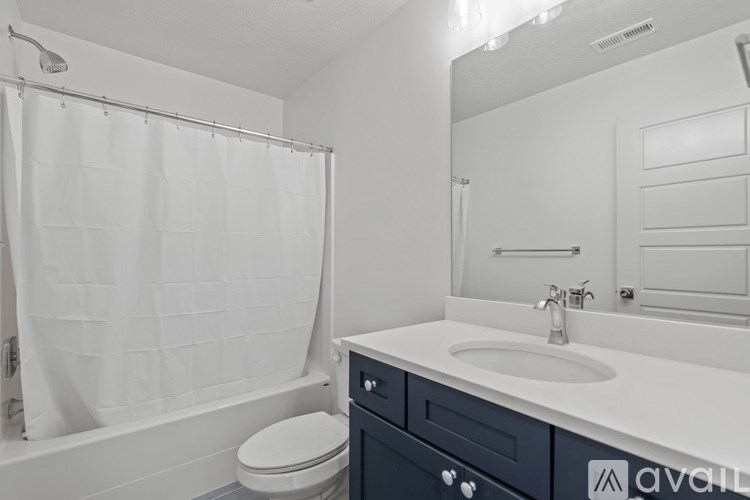 A white bathroom with a toilet, sink, and shower.