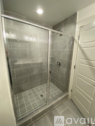 A shower with a glass door and tiled walls.