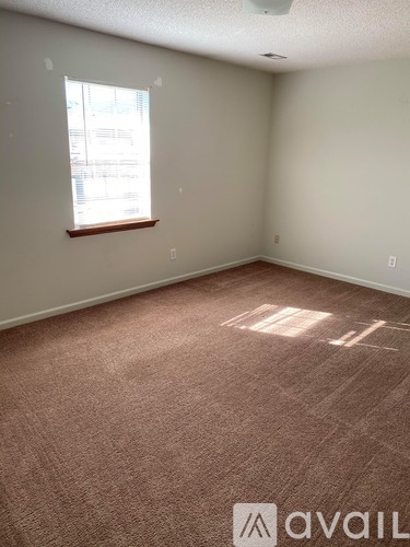 A room with a carpeted floor, a ceiling fan, and a window with blinds.