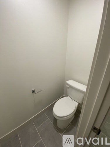 A white toilet in a small bathroom with grey tiles.