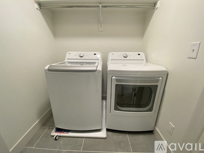 Two white front loading washing machines in a small laundry room.