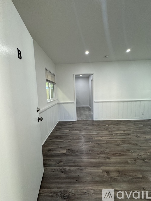 A spacious room with wooden flooring and white walls.