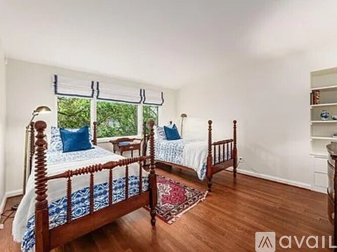 A bedroom with two beds and a window with blinds.
