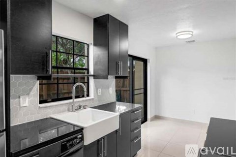 A modern kitchen with black cabinets and a white sink.