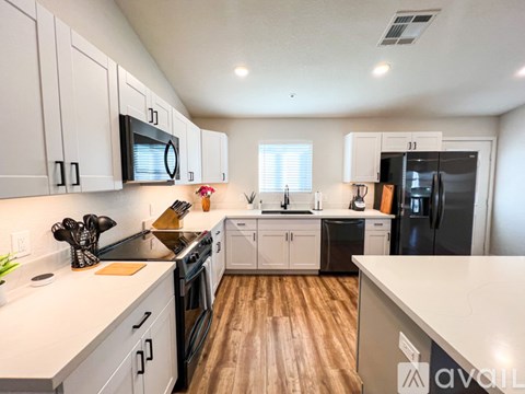 A kitchen with white cabinets and a black fridge.