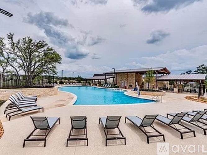 A pool surrounded by lounge chairs and a cloudy sky.