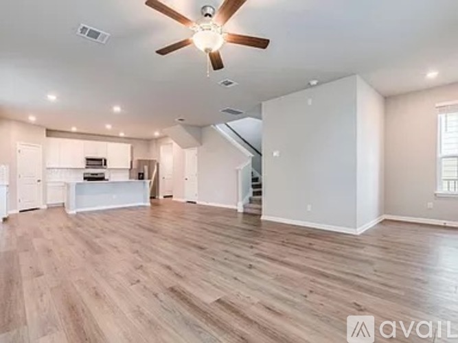 A spacious living room with a ceiling fan and hardwood flooring.