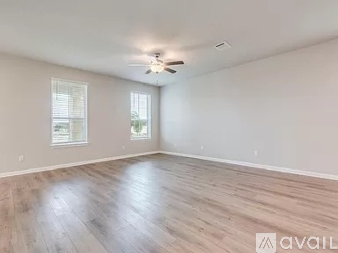 A spacious room with a ceiling fan and wooden flooring.