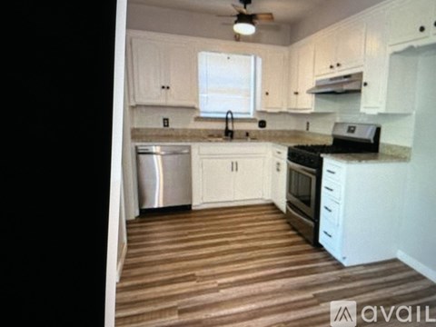 A kitchen with white cabinets and a wooden floor.