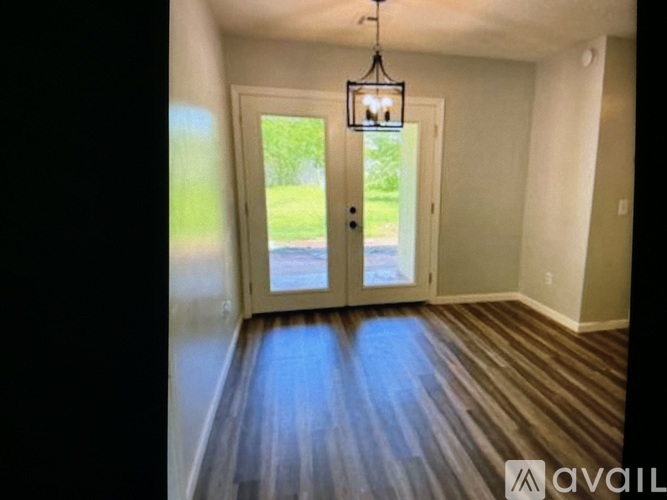 A room with a wooden floor and a door leading outside.
