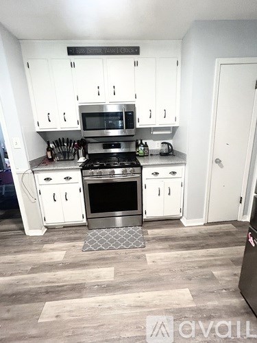 A kitchen with white cabinets and a stainless steel stove top oven.