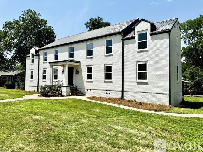 A white house with a black roof and a small porch.