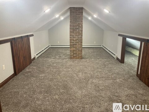 A room with a brown door and a window with white curtains.