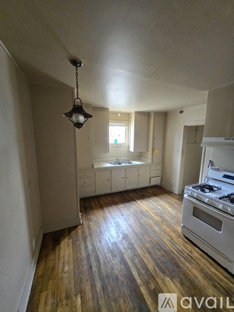 A kitchen with a stove and a hanging light fixture.