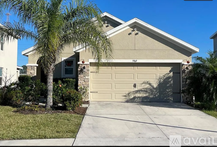 A house with a garage and a palm tree in front.