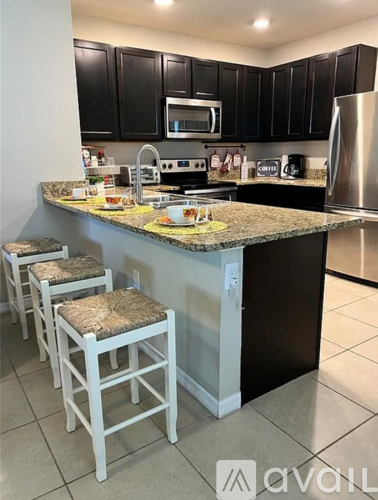 A kitchen with black cabinets and a granite countertop.