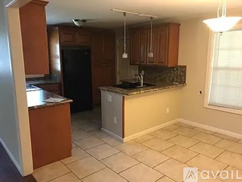 A kitchen with a black refrigerator and wooden cabinets.