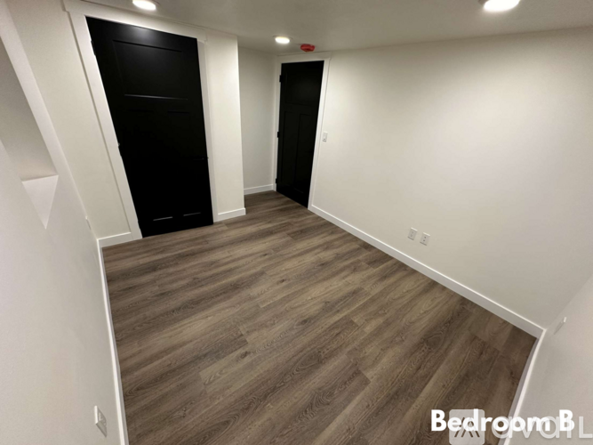 A bedroom with a wooden floor and white walls.