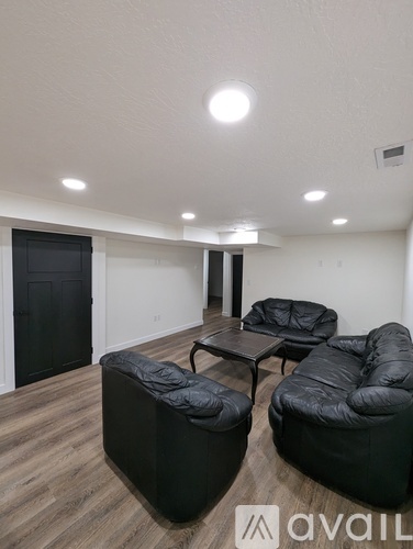 A living room with black furniture and a wooden floor.