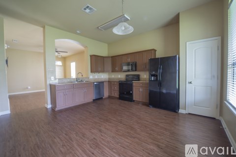 A kitchen with wooden floors and a black refrigerator.