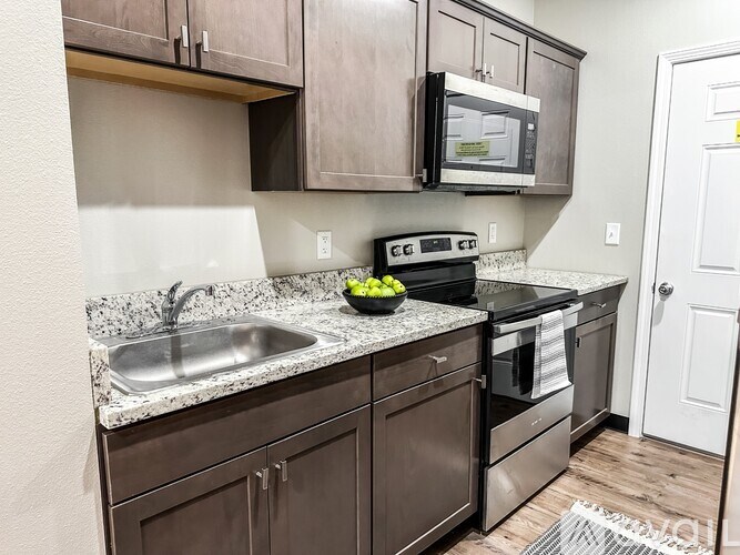 A kitchen with brown cabinets and a black microwave.