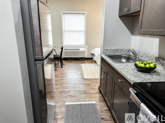 A kitchen with a black fridge, black oven, and a black chair.