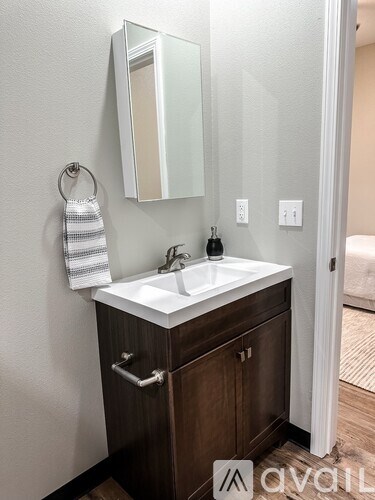 A bathroom sink with a mirror above it and a towel hanging on the wall.