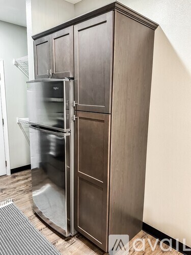A stainless steel refrigerator with its door open is in a room with wooden flooring.