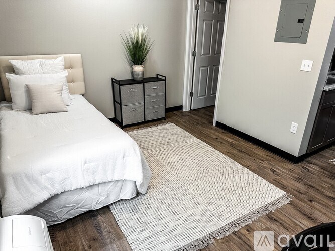 A bedroom with a bed, nightstand, and a plant.